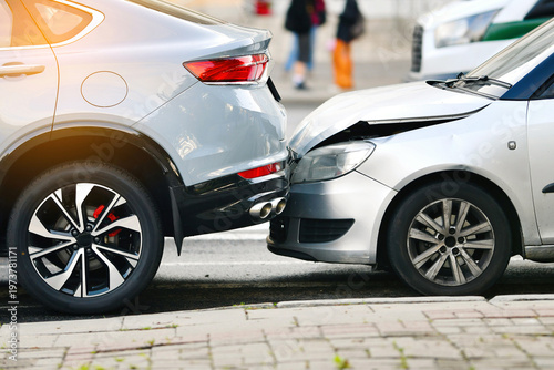 Photos Rear end collision between two cars on urban street with visible damage to bumper and hood, traffic accident