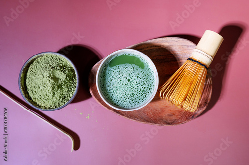 Smooth matcha drink with foam in a glass, paired with bamboo whisk and spoon.