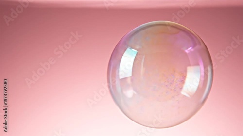 Clear glass sphere reflecting light on soft pink gradient background