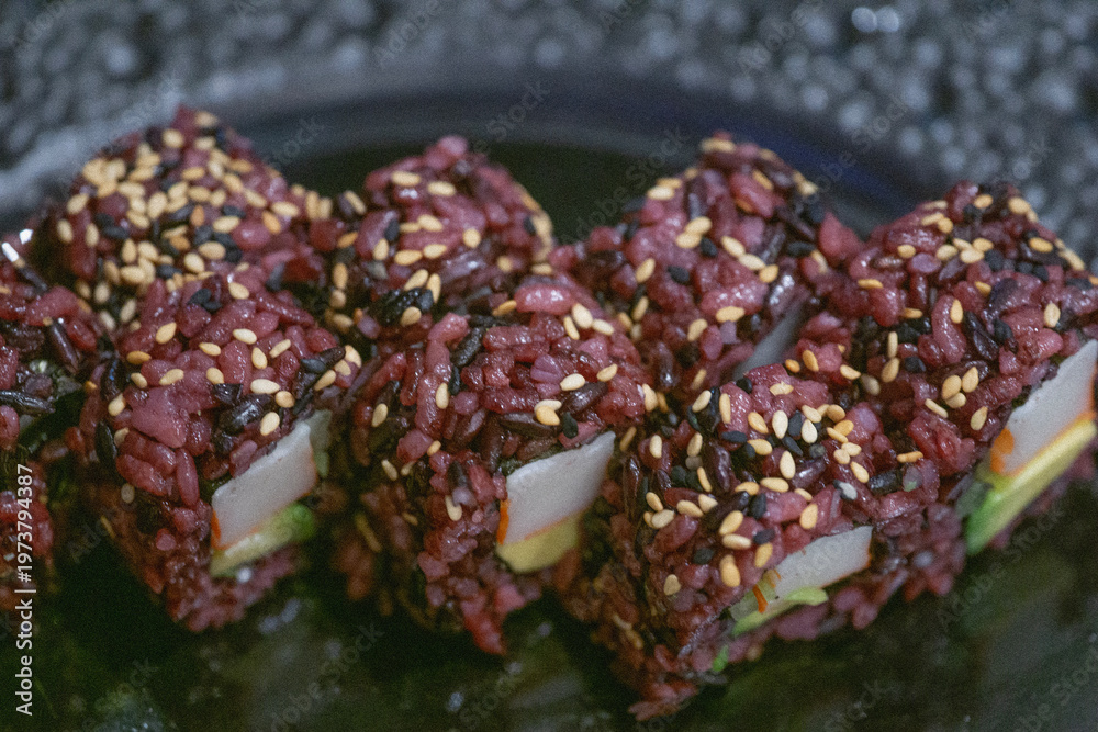 Fototapeta premium black rice sushi rolls background purple dark grains surface close up japanese uramaki with sesame seeds avocado and crab sticks concept of gastronomy, restaurant, healthy eating
