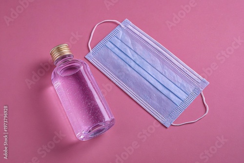 Hand Sanitizer and Surgical Face Mask on Pink Background