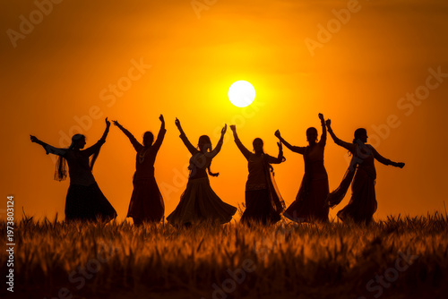Silhouetted bhangra dancers in grassy field at sunset with bright sun