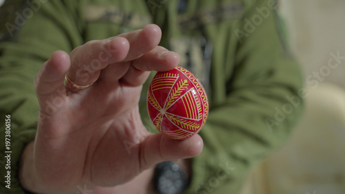 Close-up of hands painting a traditional Ukrainian Easter egg (Pysanka) with beeswax using a stylus (pysachok), preserving ancient folk traditions and symbols.
