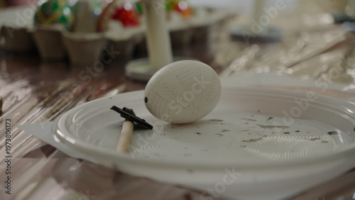 Close-up of hands painting a traditional Ukrainian Easter egg (Pysanka) with beeswax using a stylus (pysachok), preserving ancient folk traditions and symbols.
