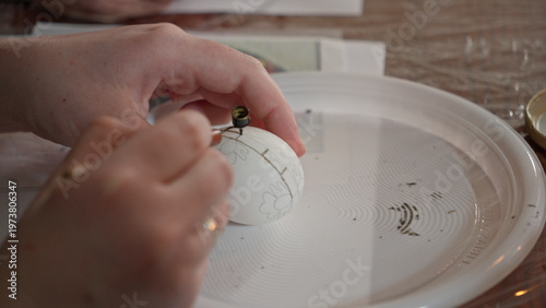 Close-up of hands painting a traditional Ukrainian Easter egg (Pysanka) with beeswax using a stylus (pysachok), preserving ancient folk traditions and symbols.