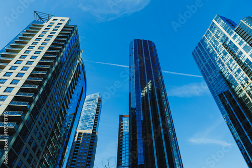 фотографія Skyscrapers reach towards a blue sky in an urban area during the afternoon with