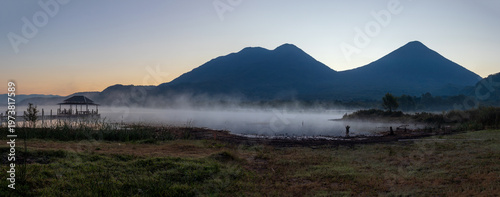 Atitlan lake with fog or mist at sunset with volcanos toliman and atitlan in the background. Tranquility and idyllic atmosphere perfect for relaxation
