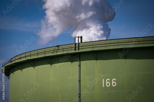 Aboveground Petroleum Storage Tank with a steam cloud behind at a refinery in Washington state. These tanks are large containers that rest on the ground’s surface commonly used for substances like oil