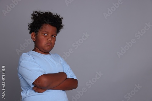 фотографія Portrait of resentful little boy with crossed arms on grey background