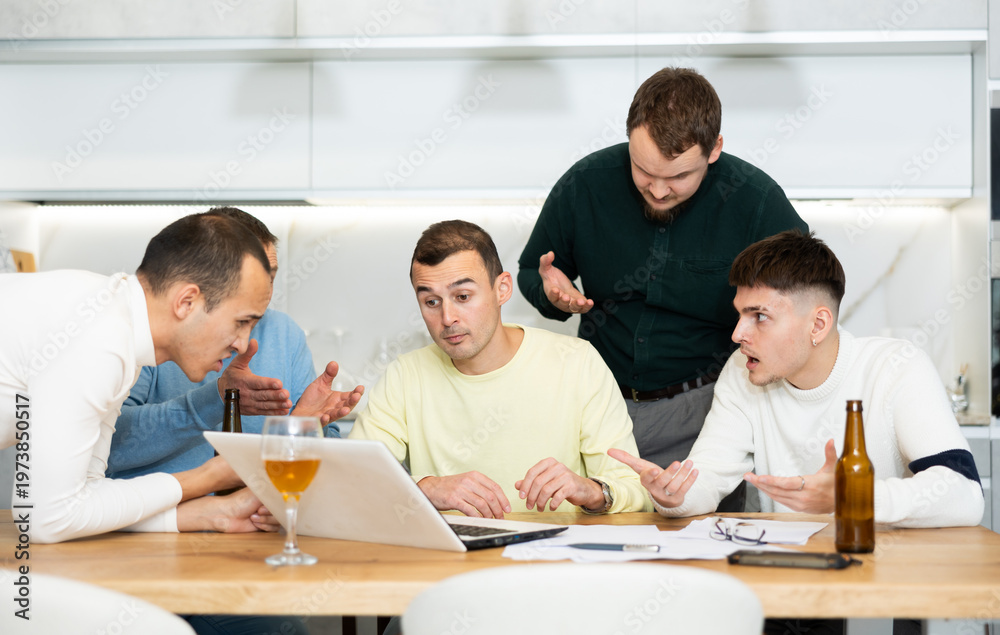 Fototapeta premium Concerned group of friends offering support to upset man receiving bad news, gathering together around laptop at home table during informal meeting with beer