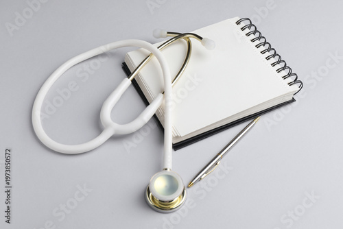 Fotografía White stethoscope, notepad and pen on grey background