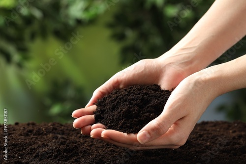 Woman with fresh soil on blurred background, closeup