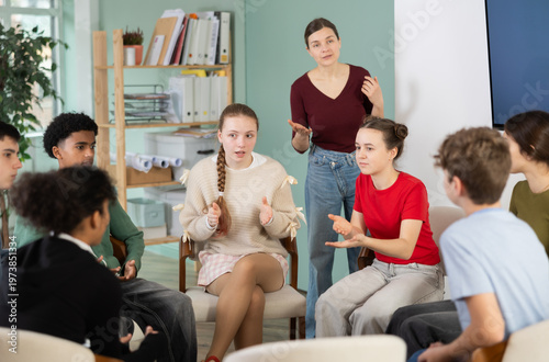 Obraz na plátně Collaborative teenage students sitting in circle and talking under supervision o
