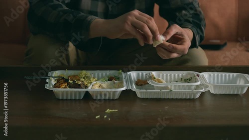Man finishing takeaway food on the sofa at home