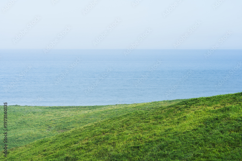 Fototapeta premium Green Coastal Hills Overlooking Calm Blue Sea Horizon