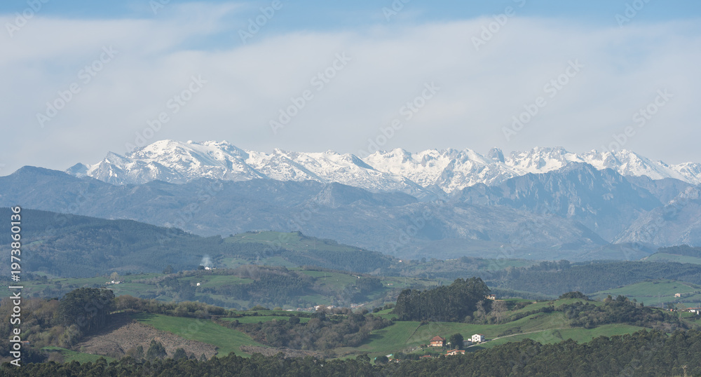 Fototapeta premium Snow Capped Mountain Range Above Green Countryside