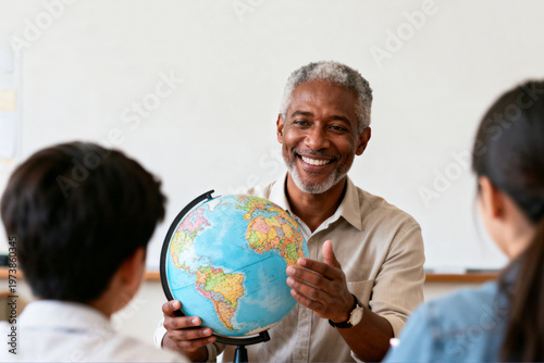 Elderly man smiling while teaching geography with a globe in classroom  