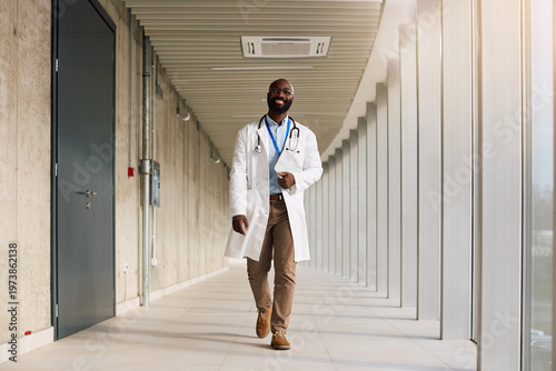 Tableau sur toile Happy black doctor walking through hallway at medical clinic.
