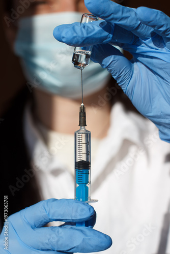 The process of extracting medicine from an ampoule. Ampoule and syringe close-up in the hands of a doctor.