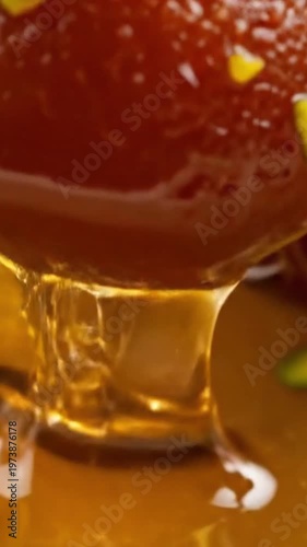 Close-up of sweet syrup being poured over delicious Indian dessert gulab jamun
