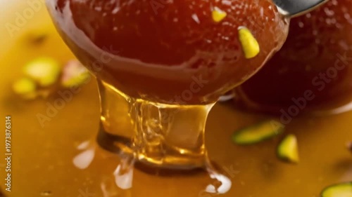Close-up of delicious Gulab Jamun dessert being forked and drizzled with syrup