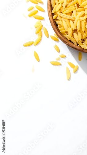 A small wooden bowl filled with orzo pasta on a white surface