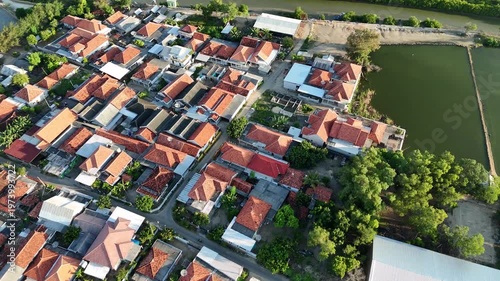 Aerial View of Dense Residential Area with Red Tiled Roofs Near Salt Ponds at Afternoon.