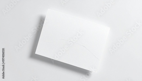 A blank white card is placed on a white surface, creating a simple and minimalist scene