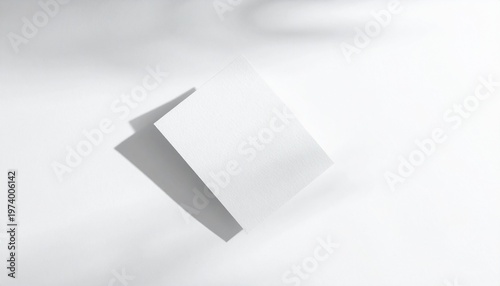 Minimalist abstract composition with a white paper folding card casting a soft shadow on a white surface, suggesting a blank canvas for creativity or design