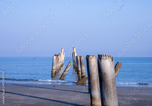 The Leaning pole at Sao Aiang Beach- Derelict concrete pier posts in the seaOld concrete pillars from an abandoned fishing pier, sticking out of the sea