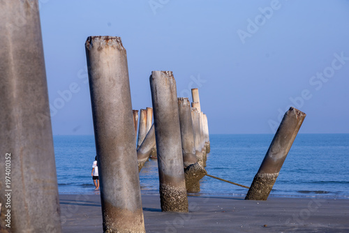 The Leaning pole at Sao Aiang Beach- Derelict concrete pier posts in the seaOld concrete pillars from an abandoned fishing pier, sticking out of the sea