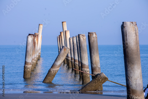 The Leaning pole at Sao Aiang Beach- Derelict concrete pier posts in the seaOld concrete pillars from an abandoned fishing pier, sticking out of the sea