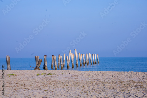 The Leaning pole at Sao Aiang Beach- Derelict concrete pier posts in the seaOld concrete pillars from an abandoned fishing pier, sticking out of the sea