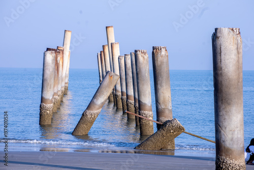 The Leaning pole at Sao Aiang Beach- Derelict concrete pier posts in the seaOld concrete pillars from an abandoned fishing pier, sticking out of the sea