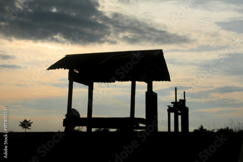A breathtaking silhouette photograph featuring a traditional wooden farm shelter, known as a 