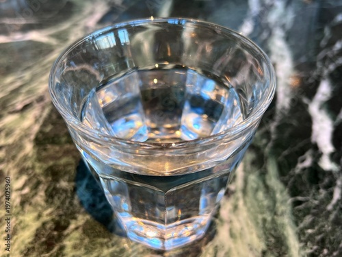 大理石模様のテーブル上の水が入ったグラス