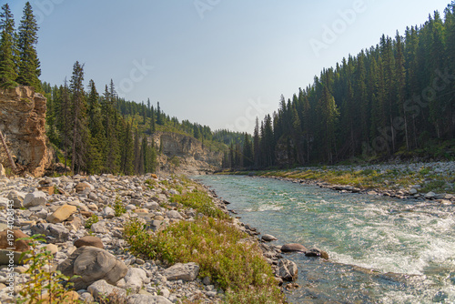 Scenic summer landscape of Elbow Falls in Kananaskis Country, Alberta, Canada. Beautiful waterfall cascading over rocky cliffs into the Elbow River with evergreen pine forest and blue sky Canada