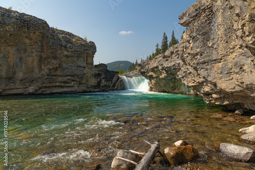 Scenic summer landscape of Elbow Falls in Kananaskis Country, Alberta, Canada. Beautiful waterfall cascading over rocky cliffs into the Elbow River with evergreen pine forest and blue sky Canada