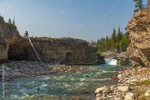 Scenic summer landscape of Elbow Falls in Kananaskis Country, Alberta, Canada. Beautiful waterfall cascading over rocky cliffs into the Elbow River with evergreen pine forest and blue sky Canada