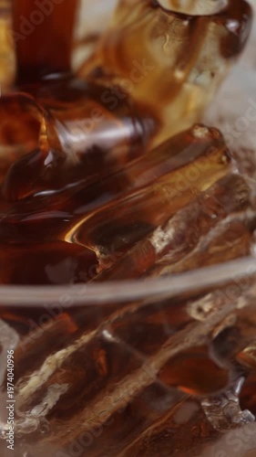 4K Vertical video Close-up of iced black coffee with ice cubes showing rich dark liquid and refreshing texture, Cold brew or americano concept perfect for cafe menu summer drinks and commercial use.