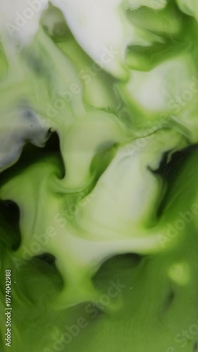 4K Vertical video Abstract green tea or matcha liquid mixing with milk creating smooth swirling patterns Organic fluid texture with vibrant green tones, ideal for beverage concept background and moder