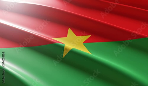 Close-up view of the national flag of Burkina Faso waving with a vibrant red and green design and a prominent yellow star in the center, illuminated by a soft light.
