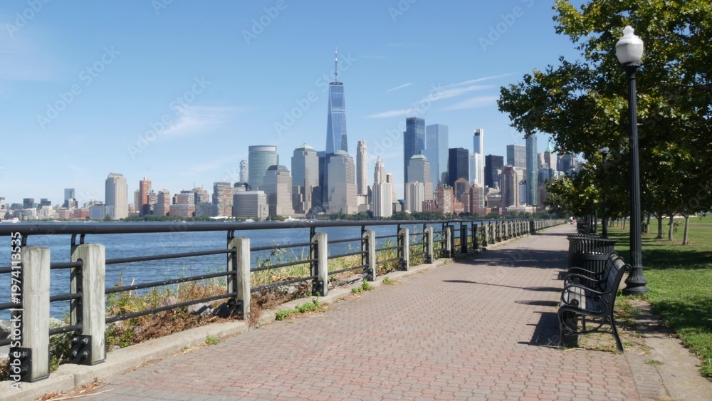 Fototapeta premium New York City Manhattan Downtown Financial District skyline, World Trade Center tower, cityscape from New Jersey Liberty state park, United States. Hudson river waterfront walkway, skyscraper building