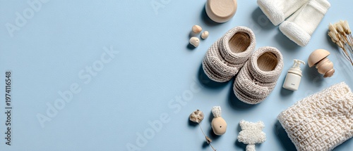Handcrafted soft knitted baby booties rest beside natural wooden toys and textured fabric on a calm light blue surface for a gentle nursery atmosphere