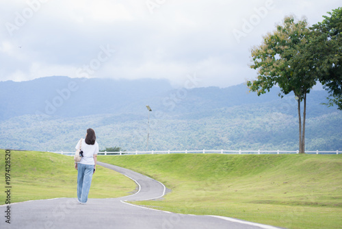 Relax and wellness concept with woman walk on road in garden and mountain background at chiangmai thailand in raining season