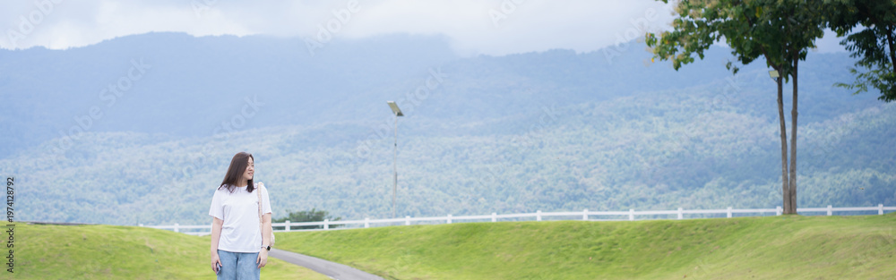Fototapeta premium Relax and wellness concept with woman walk on road in garden and mountain background at chiangmai thailand in raining season
