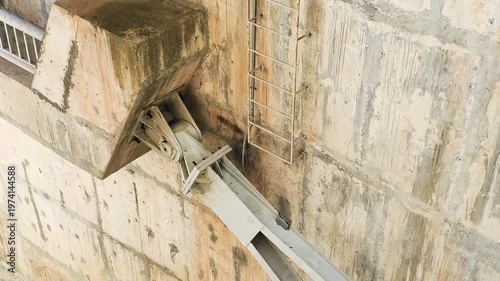 Dam gate and anchor joint connect heavy steel arm to reinforced concrete wall. Massive industrial hinge allows for structural movement and load distribution. This dam gate part relies on anchor joint.