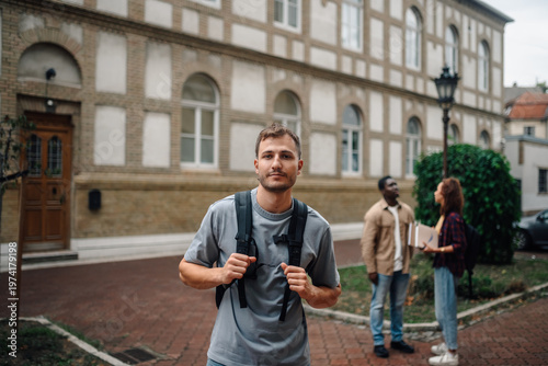 University student standing in front of university building with backpack