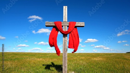 Wooden Cross with Red Cloth in Green Field Under Blue Sky