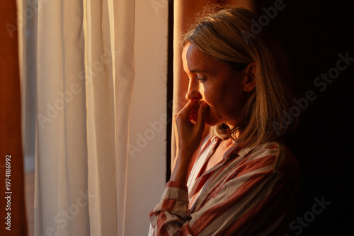 Stressed middle aged Woman standing at home near window. Unhappy woman